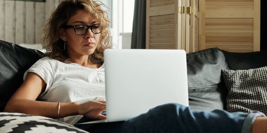 The picture shows a woman reading on her laptop with her progressive glasses on