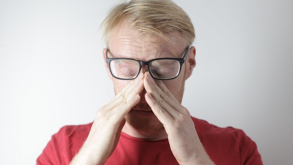 this picture shows a man with his glasses rubbing his eyes